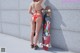 A woman in a red bikini standing next to a skateboard.