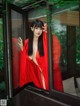 A woman in a red robe is looking out of a window.