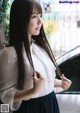 A woman with long black hair standing next to a car.