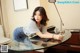 A woman leaning over a glass table with a laptop.