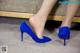 A close up of a woman's legs wearing blue high heels.