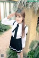 A woman in a school uniform salutes at the camera.