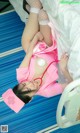 A woman in a pink nurse outfit laying on a hospital bed.