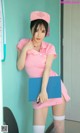 A woman in a pink uniform holding a blue folder.