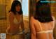 A woman in a white bra looking at herself in the mirror.