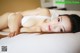 A woman laying on top of a white bed.