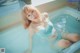 A woman in a blue bikini sitting in a bathtub.