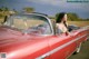 A woman sitting in the driver's seat of a red convertible car.