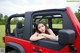 A woman leaning out the window of a red jeep.