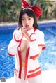 A woman in a red and white outfit posing by a pool.