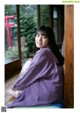 A woman in a purple kimono sitting on a wooden floor.